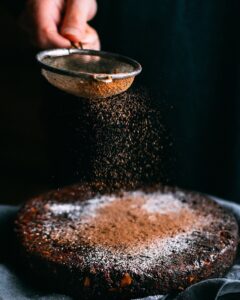 Verein PriseMUT - person pouring chocolate powder on cake